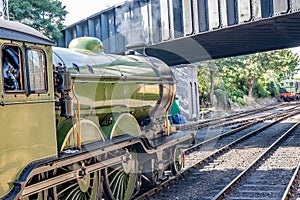 Side view of a green steam train on the rail tracks