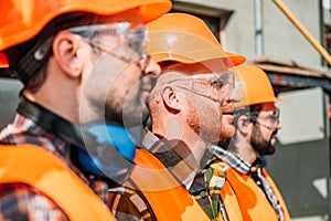side view of group of equipped builders standing