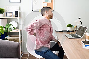 Side view of a guy at the office suffering from a back injury