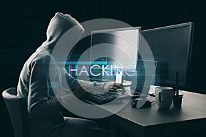 Side view of hacker at desktop using computers with abstract creative digital text hologram on dark background. Hacking,