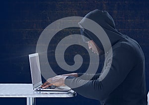Side view of hacker using a laptop in front of blue background