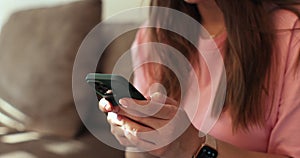 Side view. Hand of woman using smartphone at home. Close up of female hands texting on smartphone. Technology concept.