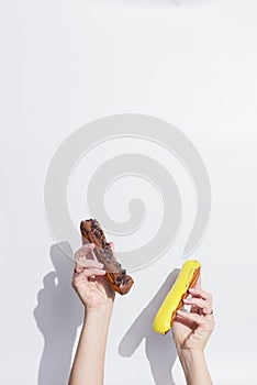 Side view of hands with traditional french eclairs over white background with copy space.