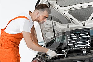 side view of handsome auto mechanic auto mechanic fixing car with wrench
