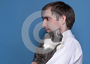 Side view of handsome man in pink shirt holding adorable grey cat on sholder