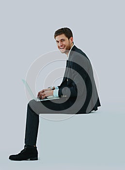 Side view of a handsome young business man sitting on a white modern chair.