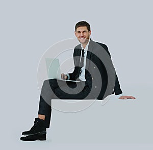 Side view of a handsome young business man sitting on a white modern chair.
