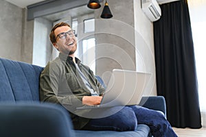Side view handsome young businessman in eyewear working with computer. Pleasant happy man communicating in social