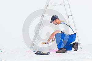 Side view of handyman in overalls opening paint can