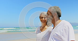 Side view of happy active senior African American couple walking on beach in the sunshine 4k