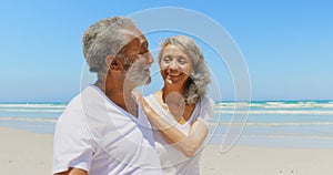 Side view of happy active senior African American couple walking on beach in the sunshine 4k