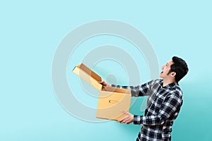 Side view of happy customer asian man smiling opening and holding box looking up to copy space