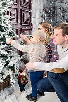 Side view of happy family decorating Christmas tree at home. Con