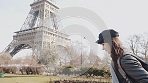 Side view happy freelance photographer woman walking along autumn Paris street at Eiffel Tower on vacation slow motion.