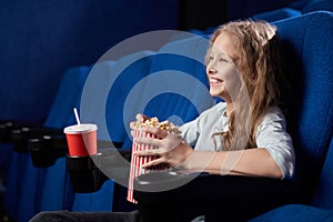Side view of happy girl laughing at funny comedy in cinema