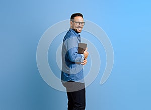 Side view of happy male professional with digital tablet looking at camera against blue background