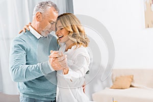 side view of happy mature couple dancing face to face