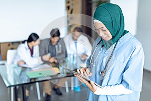 Happy female surgeon in hijab using digital tablet in the hospital