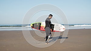 Side view of happy surfer with disability going along coastline