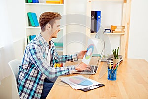 Side view of happy worker holding diagrama and typing on laptop photo