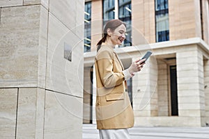 Side view of happy young businesswoman looking at smartphone screen