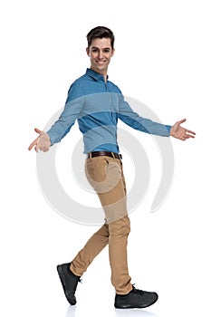 Side view of happy young man walking and opening arms