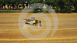 Side view of the harvester red and blue tractor, producing cleaning yellow rapeseed at farmers ` fields. The raw