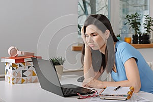 Pretty brunette bored young woman sit at home office look away has no desire to work at laptop, annoying monotonous work photo