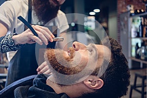 Bearded young man ready for shaving in the hair salon of a skill