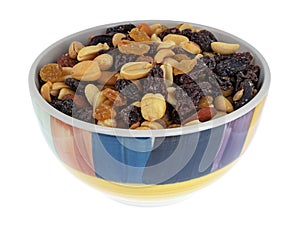 Side view of high energy trail mix with roasted nuts and fruit in a colorful bowl isolated on a white background