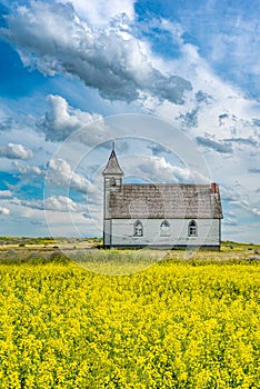 Side view of the historic Peace Lutheran Church in Stonehenge, SK with a canola field in the foreground