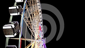 Side view of huge Ferris wheel rotating at amusement park under dark night sky