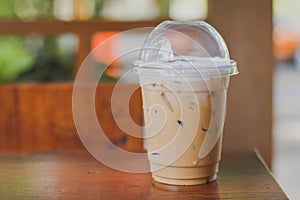 Side view Ice coffee cappuccino, latte, mocha in plastic cup with water drop on wooden column with blurry garden background with