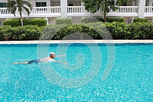 Side view image of happy elderly caucasian swimming in pool during retirement holiday with relaxation and smiling