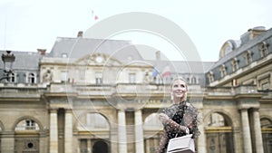 Side view of an incredible blonde woman in black dress walking and posing near beautiful historic buildings. Action