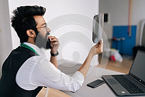 Side view of Indian male doctor in glasses examining patient chest x-ray film lungs scan at radiology department in