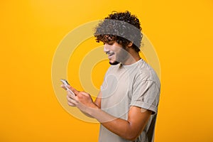 Side view at Indian man with curly hair using cellphone, typing text message