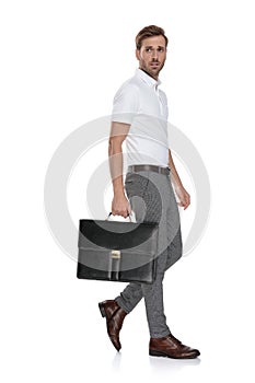 Side view of a intrigued man walking with his suitcase