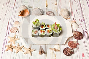 Side view of Japanese Veggie Futomaki Sushi Roll pieces with fresh vegetables on carton delivery takeaway box on wooden background