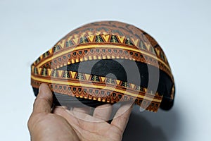 side view of a Javanese headgear (blangkon) in the hands of an Asian man,