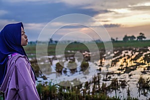 side view of a Javanese woman looking at the orange sky.