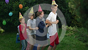 Side view joyful kids dancing in row laughing standing in sunshine outdoors. Happy relaxed Caucasian boys and girl in