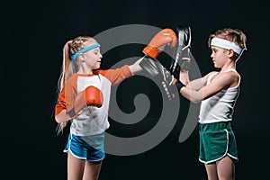 Side view of kids pretending boxing isolated on black photo