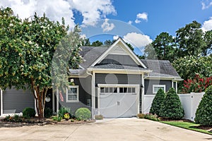 The side view of a large gray craftsman new construction house with a landscaped yard and a garage and driveway