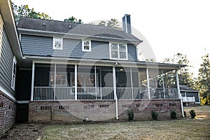 Side view of a large two story blue gray house with wood and vinyl siding