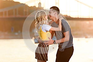 side view of laughing young couple going to kiss on river beach