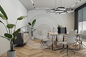 Side view on light wooden meeting table with laptop surrounded by stylish light grey chairs in conference room with circle