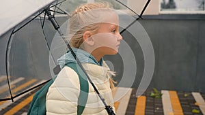 Side view little European girl going walking street city outside umbrella rain stroll fresh air weather pleasure calm