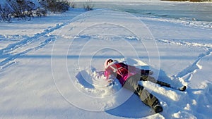 Side view little girl making snow angel. Winter kid. Sunny winter day