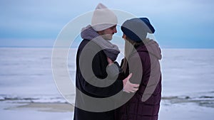 Side view loving boyfriend whispering on ear of excited girlfriend standing at background of winter landscape. Happy